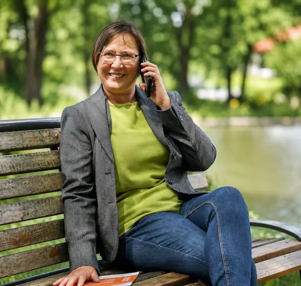 Heike König telefoniert auf einer Bank